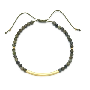 Detail von grünen facettierten Steinen und poliertem Goldrohr auf verstellbarem Armband