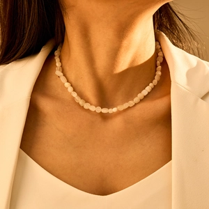 Detail van een witte onregelmatige halfedelstenen kralenketting om de nek
