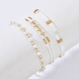 Bohemian Tila bead bracelet set with white beads and gold accents on a white stand