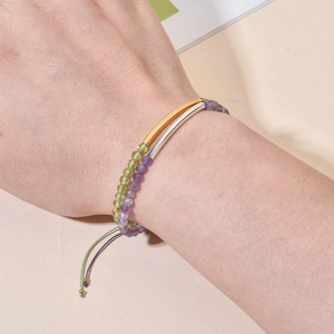 Set aus geschichteten Naturstein-Armbändern mit Gold- und Silberröhren am Handgelenk