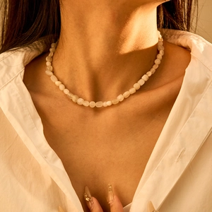 Detailopname van de bohemian halfedelsteen kralenketting op een wit overhemd met kraag