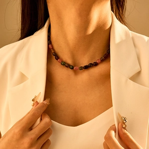 Detail van bohemien halsketting met halfedelstenen op model in een wit pak