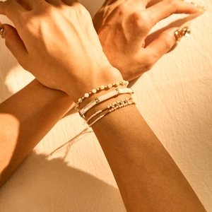 Detail of bohemian white Tila bead and crystal charm bracelet set on a model's wrist