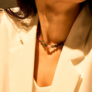 Detail van kleurrijke edelsteen kralenketting gedragen op een wit pak in boho-stijl