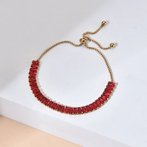 Adjustable gold tennis bracelet with rectangular red ruby zircons on a white platform