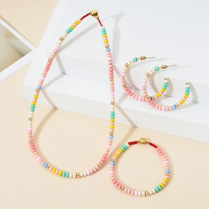 Close-up of macaron color beaded jewelry set with gold accents and red woven cords