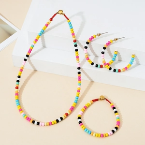 Detail of colorful bohemian beaded jewelry set with woven necklace and C-hoop earrings