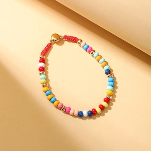 Close-up of a colorful beaded bracelet with red woven cord and gold metal clasp