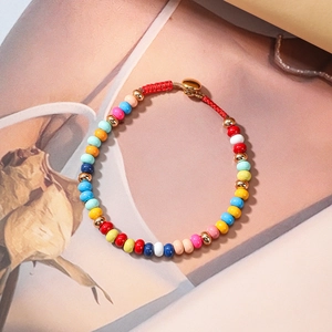 Classic luxury bracelet with colorful beads and gold metal accents on a floral background