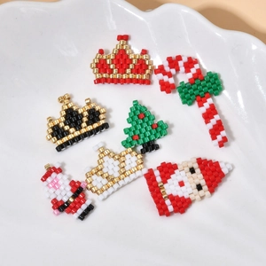 Handcrafted Christmas beaded charms featuring Santa and tree on a white ceramic plate