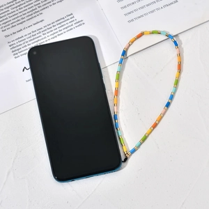 Colorful beaded phone lanyard with gold spacers on a smartphone over a white table