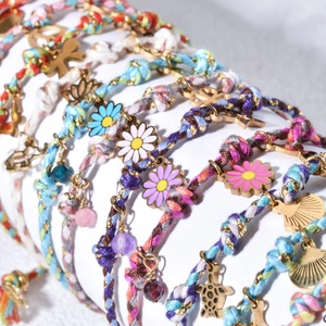 Macro detail of Bohemian gold-plated ocean-themed braided bracelets with shell charms