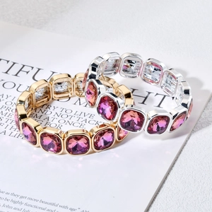 Gouden en zilveren armbanden met grote paarse vierkante kristallen op tijdschrift
