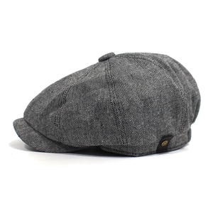 Detail der Schiebermütze aus Tweed mit Metall-Logo-Knopf und strukturierter Webart
