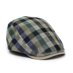 Detailed view of British style plaid flat cap with green and blue tartan fabric texture