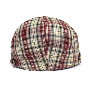 Close-up of red and black plaid newsboy cap featuring an adjustable metal side buckle