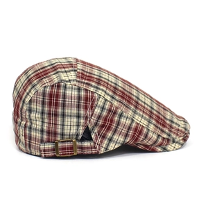 Detail of checkered newsboy cap showing adjustable bronze metal buckle and fabric texture