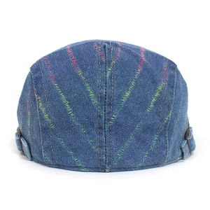 Detail der blauen Denim-Schiebermütze mit bunten Stickereien und seitlicher Metallschnalle