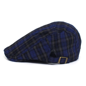 Detail of adjustable metal bronze buckle on the side of a blue plaid newsboy cap