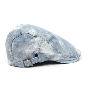 Detail view of washed denim flat cap showing metal buckle and stitching texture