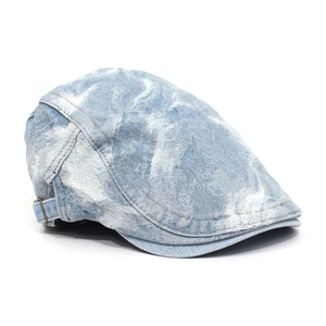 Detail of washed denim beret featuring vintage jacquard pattern and adjustable metal buckle