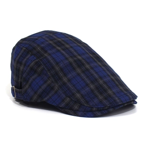 Close-up of blue and black plaid flat cap showing metal side adjustment buckle detail