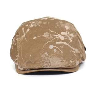 Detailed close-up of khaki cotton flat cap with white ink splash pattern and fine stitching