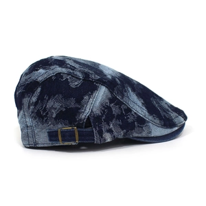 Detail of blue washed denim beret featuring a vintage brass metal adjustment buckle