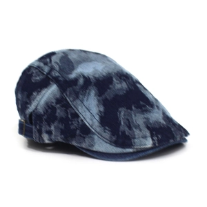 Close-up of vintage washed denim beret featuring adjustable gold metal buckle and tie-dye pattern