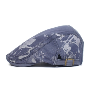 Detail of blue cotton hunting cap featuring grey paint splatter print and metal buckle