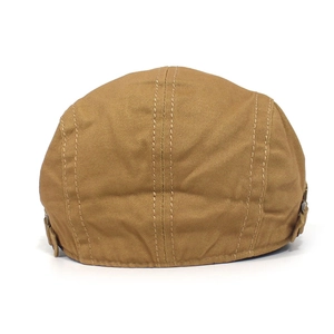 Detail view of cotton newsboy cap with adjustable metal buckles on the side in brown