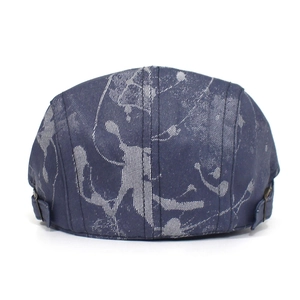 Detail view of denim flat cap featuring artistic white splash print and back buckle