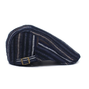 Detail of adjustable bronze metal buckle on a navy striped cotton flat cap