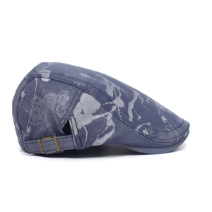 Detail of blue patterned flat cap featuring bronze metal buckle and denim texture