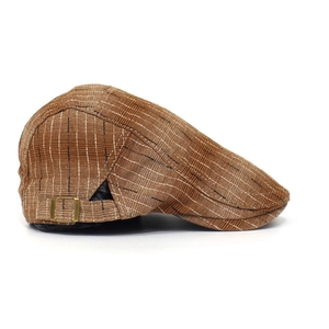 Détail du béret marron montrant la texture rayée et la boucle métallique vintage
