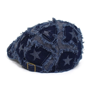Detail der verwaschenen Jeans-Baskenmütze mit Stern-Patchwork und Metallschnalle