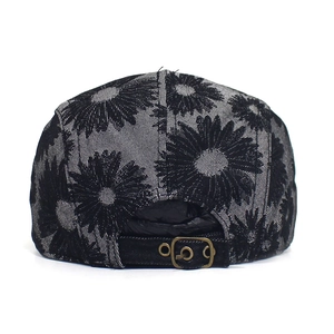 Detail view of cotton floral newsboy cap featuring adjustable metal buckle and daisy print