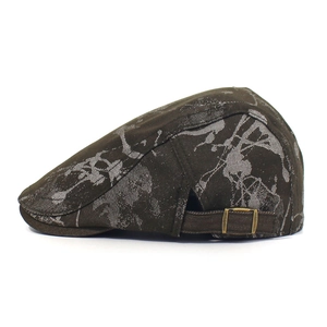 Close-up of printed brown cotton newsboy cap with vintage ink-splat pattern and brass buckle