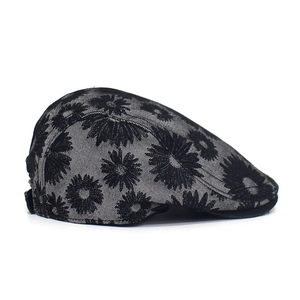 Detail view of cotton newsboy hat featuring elegant black daisy floral print patterns