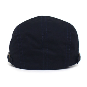 Detail of dark blue cotton newsboy hat featuring bronze metal side adjustment buckles