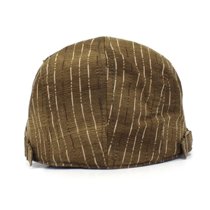 Détail du béret vintage marron rayé montrant la texture canevas et la boucle en laiton