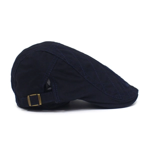 Detail of navy blue cotton ivy cap with quilted diamond pattern and bronze metal buckle