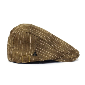Détail de la texture rayée marron et de la boucle en laiton vintage sur le béret rétro