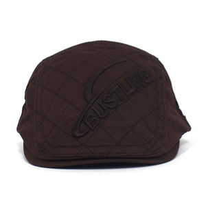 Detail view of dark brown cotton flat cap with quilted diamond pattern and embossed logo