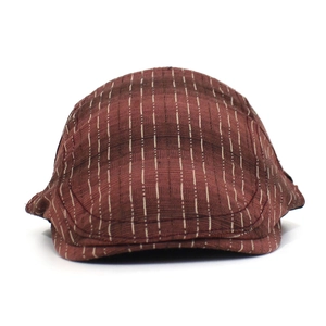 Détail de la casquette plate marron-rouge avec texture à rayures et motif à carreaux
