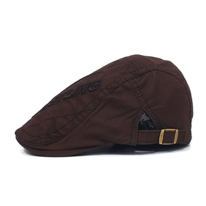 Close-up of brown quilted cotton flat cap with STLING embroidery and metal buckle