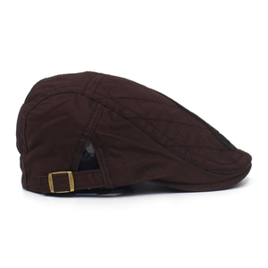 Detail of dark brown cotton flat cap showing quilted texture and metal buckle adjustment
