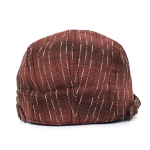 Détail de la texture rayée marron du béret et boucle métallique ajustable