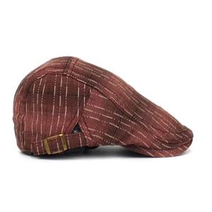 Détail du béret vintage marron-rouge avec rayures blanches et boucle en métal laiton