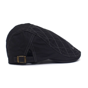 Detail of black cotton ivy cap featuring diamond quilting and antique bronze side buckle